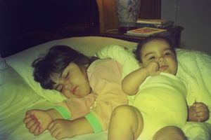 Two children sleeping peacefully on a bed with yellow bedding.