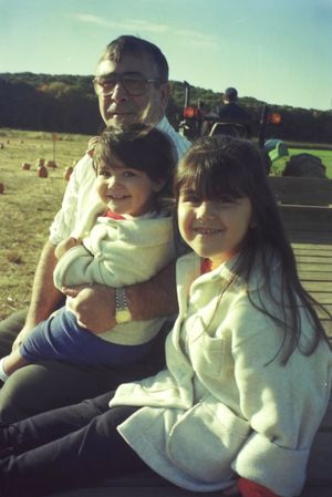 A sunny outdoor family scene with people sitting together at what appears to be a park or field.