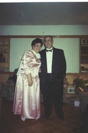 Two people in formal attire standing together in a living room.