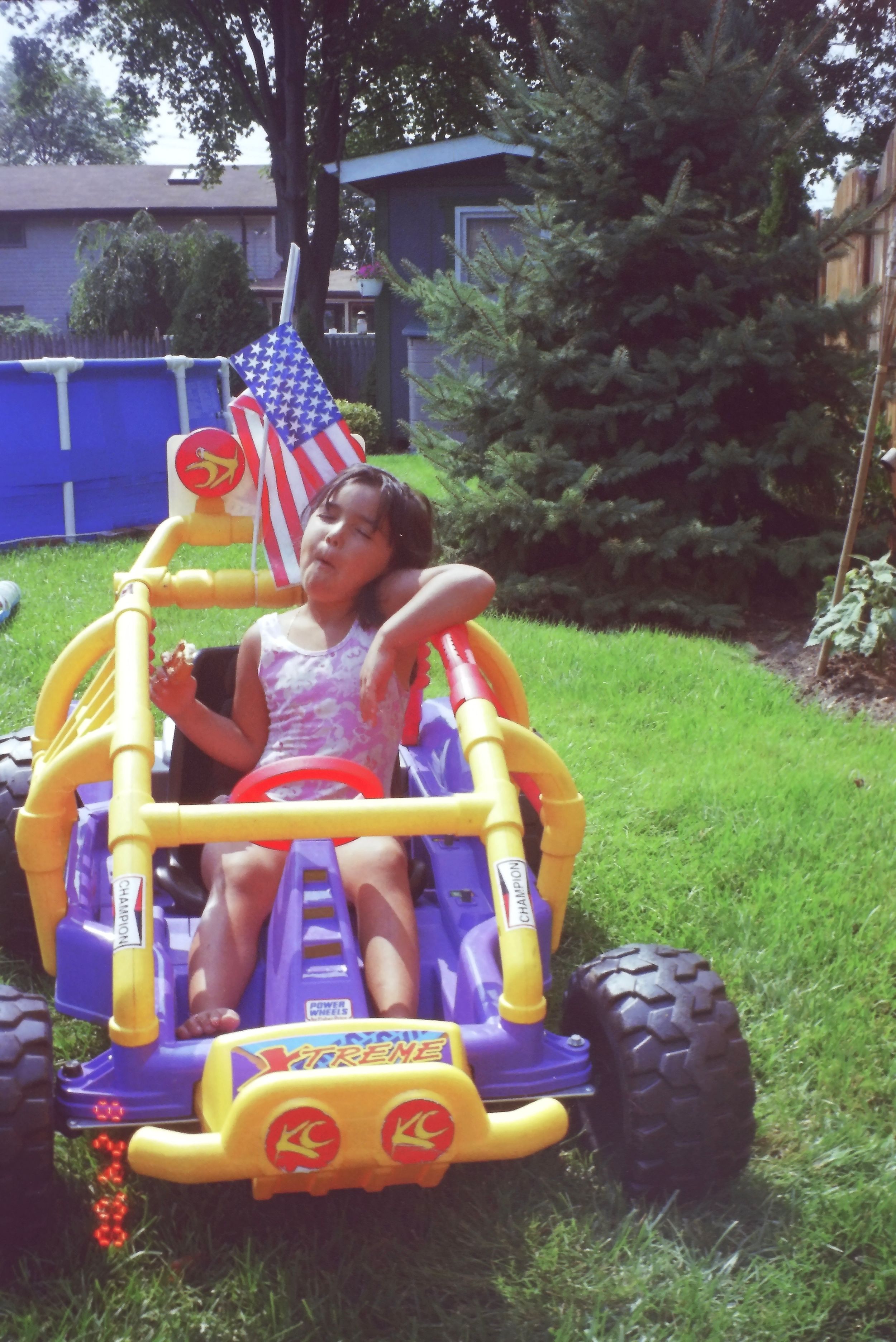 Colorful inflatable bouncer with American flags set up in a grassy backyard.