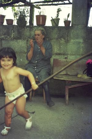 Small child playing and jumping on a covered patio with potted plants.