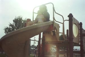 Silhouettes of playground equipment against bright sky during sunset.