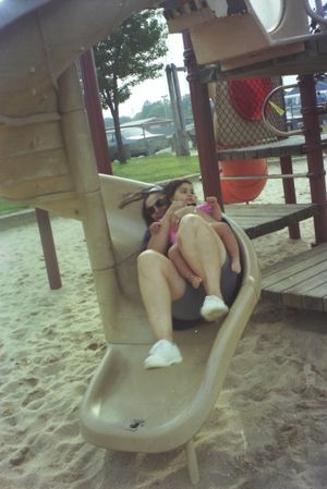 Playground equipment with curved slide in sandy play area.