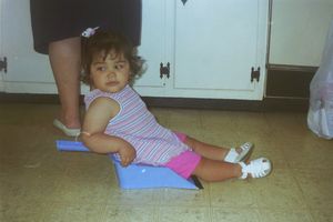 Children sitting on floor playing with toys in kitchen area.