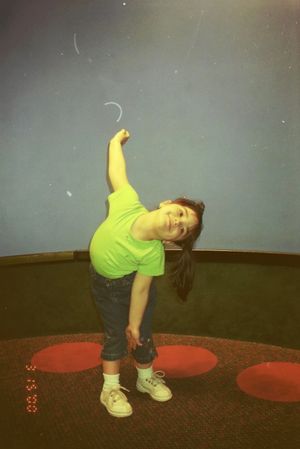 A sequence of dance moves showing someone in a yellow shirt and dark pants bending backwards on a red circular mat.
