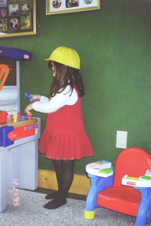 Children's play area with colorful plastic furniture and toys against a green wall.
