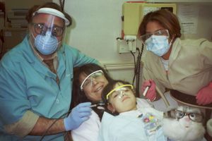 Medical professionals in protective gear working in what appears to be a dental office setting.
