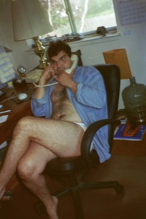 Person in blue clothing sitting at a desk while talking on the telephone.