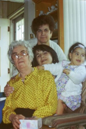 Group of people sitting together indoors, with someone wearing a yellow polka dot outfit.