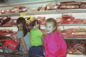 People shopping at a meat counter display case in a grocery store.