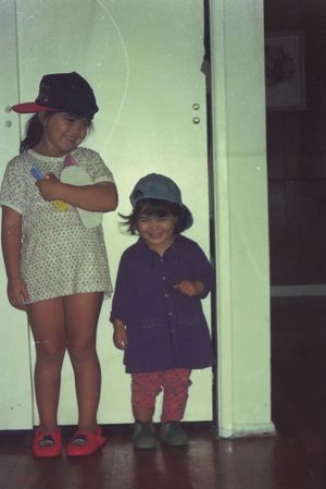 Children in casual clothing standing against a white wall.
