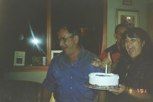 Birthday celebration with cake in a dimly lit room with multiple guests.