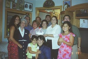 Family gathering in a home with framed photos visible on the walls.