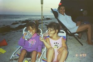 Children sitting in beach chairs along a rocky shoreline at dusk.