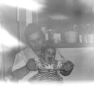 Black and white vintage photograph showing a tender family moment indoors.