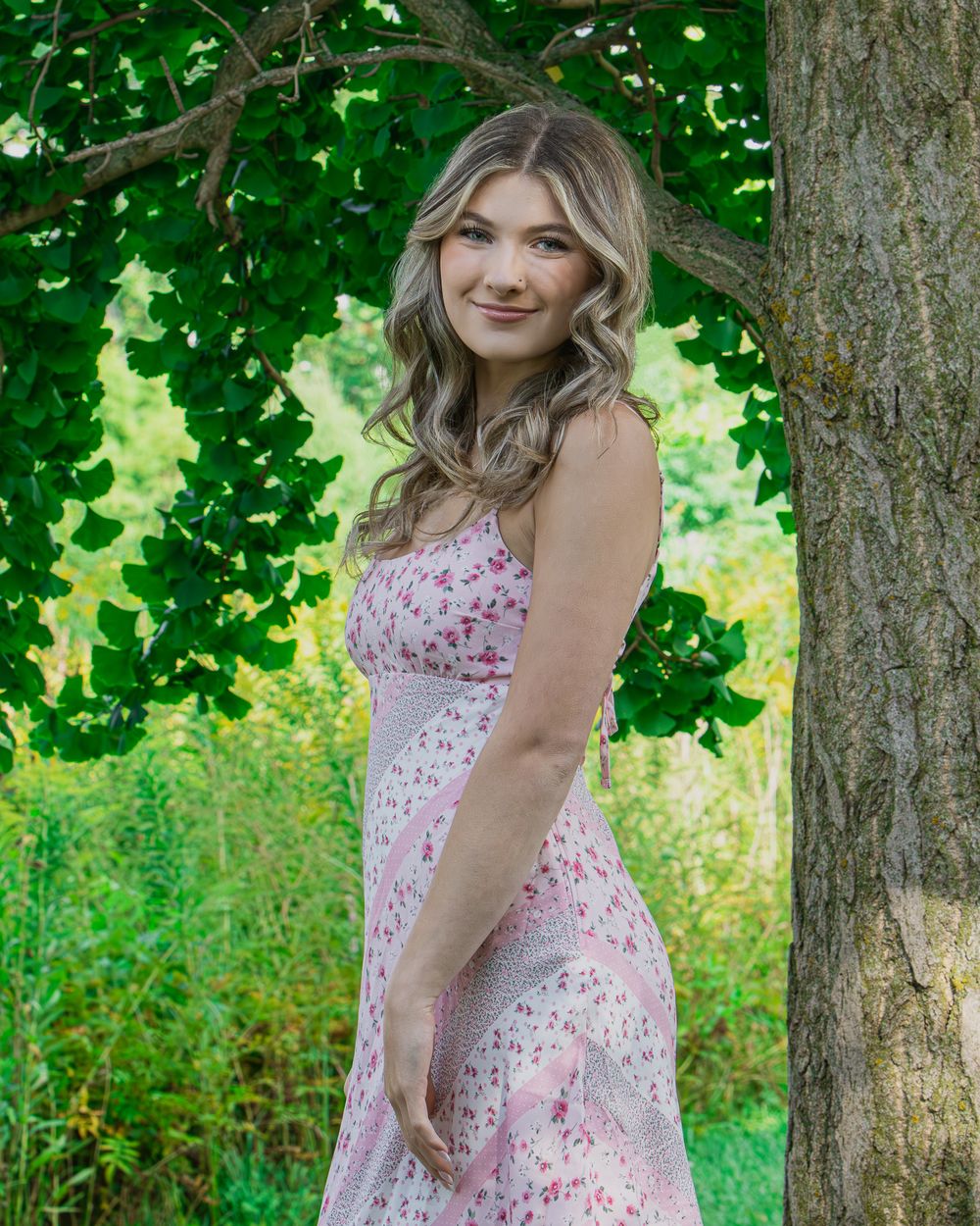 Garden photoshoot featuring floral dress and natural greenery backdrop.