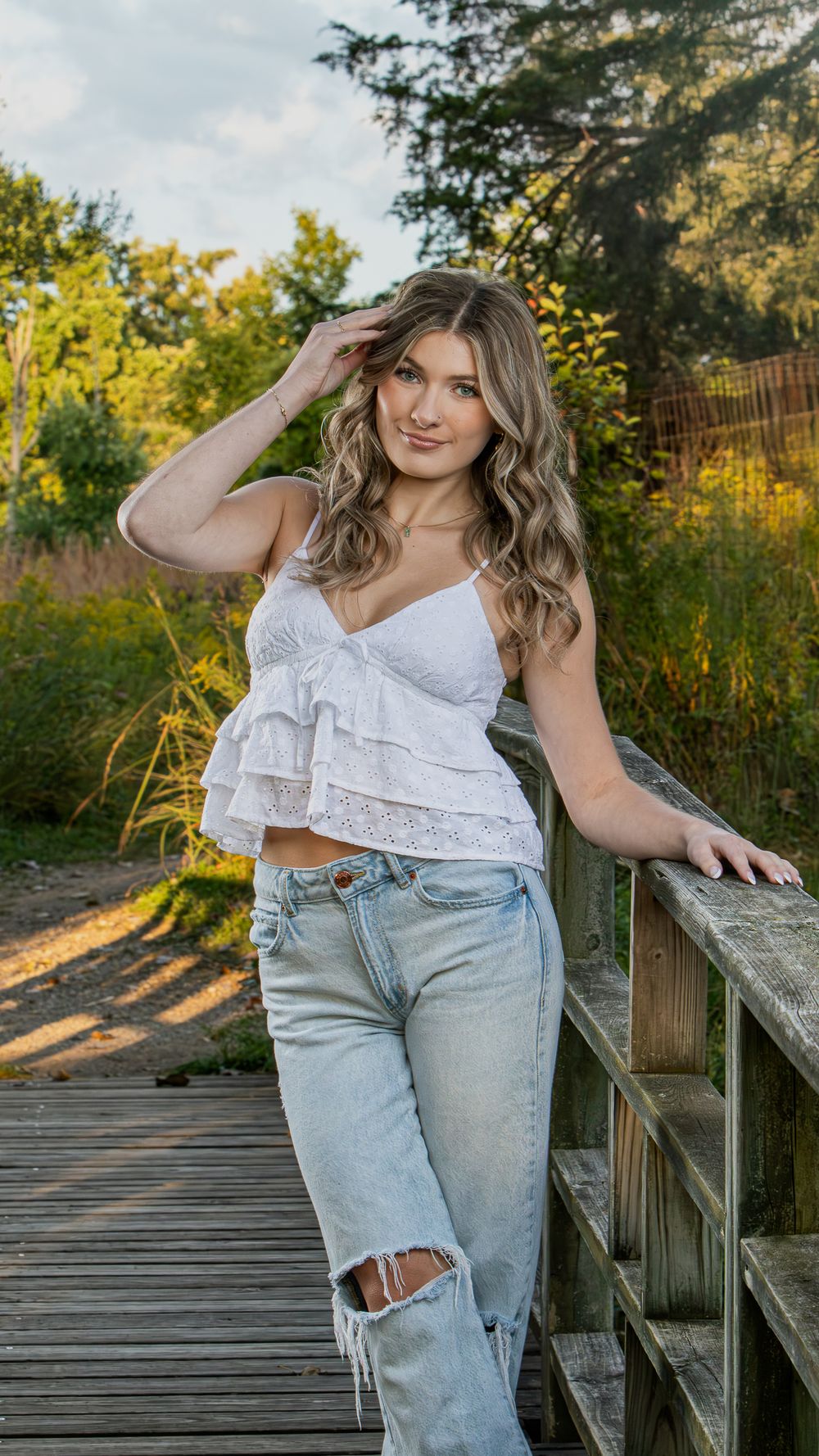 Casual fashion photography on wooden deck with ruffled top and distressed jeans.
