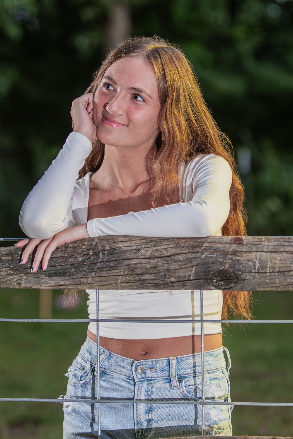 Casual outdoor portrait against rustic wooden fence in natural lighting.