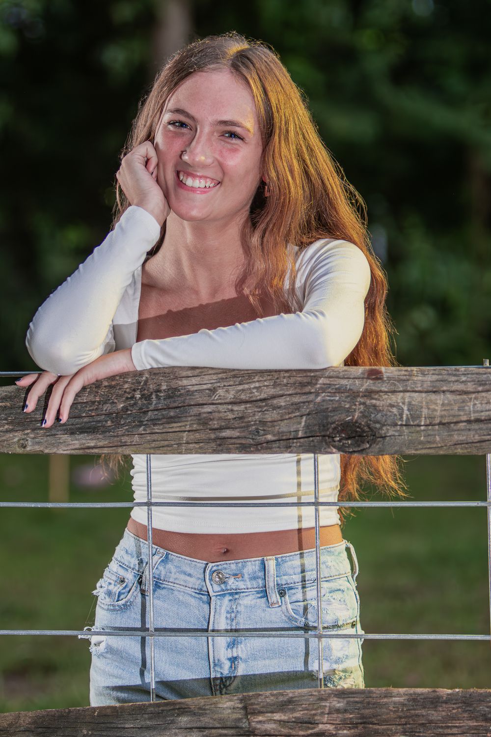 Natural light portrait session featuring casual style against wooden fence backdrop.