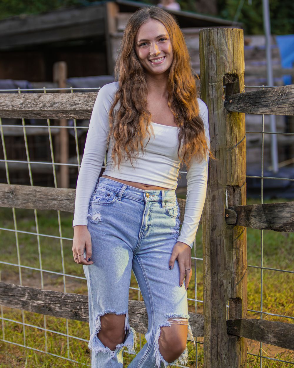 Country style portrait session by wooden fence in casual denim outfit.