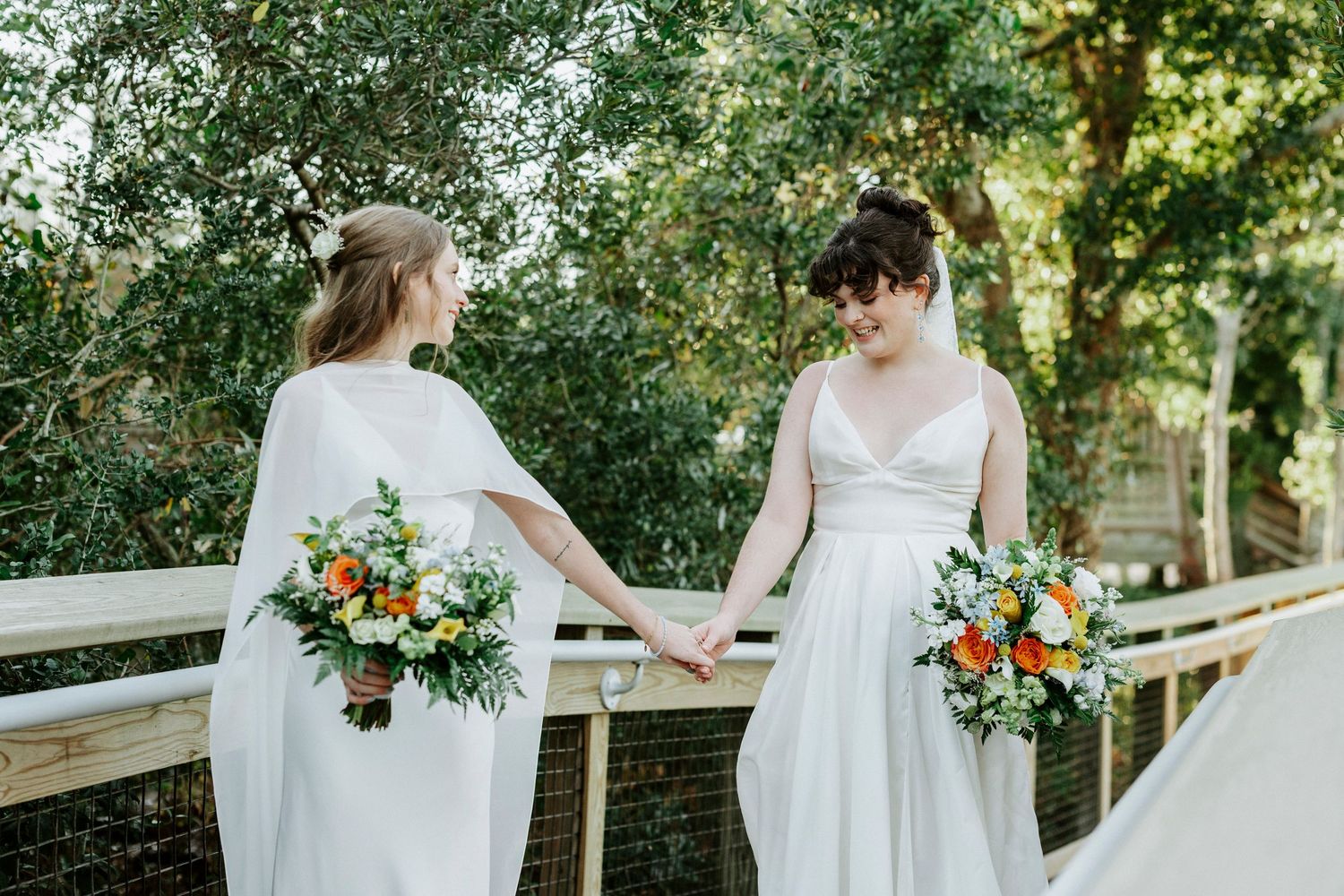 Wedding party poses in front of a white columned mansion with lush greenery and trees.