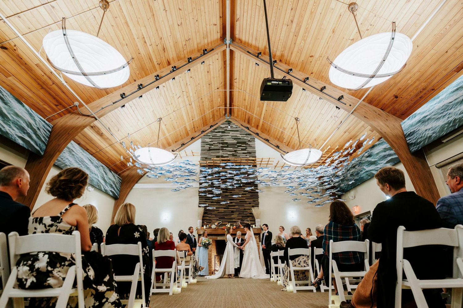Wedding ceremony setup in rustic wooden chapel with vaulted ceiling and stone accent wall.
