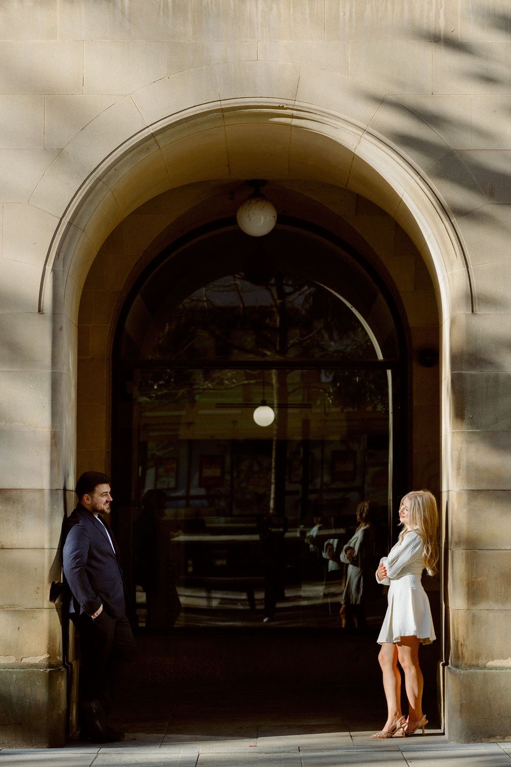 A sequence of arched stone passageways shows a couple walking and conversing in dramatic lighting and shadows.
