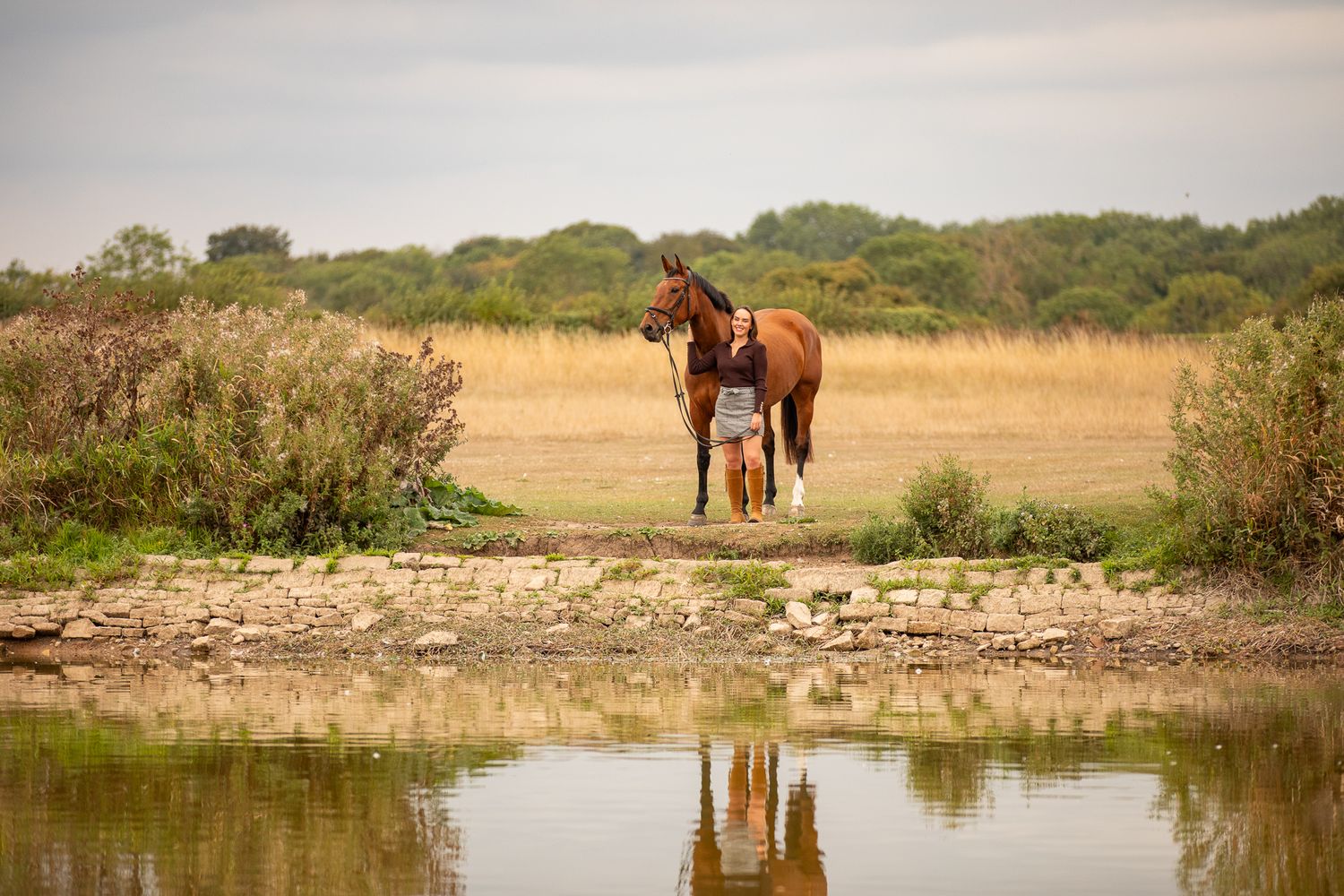 A horse and its rider enjoy an outdoor photoshoot session near rustic wooden fencing on a sunny day.