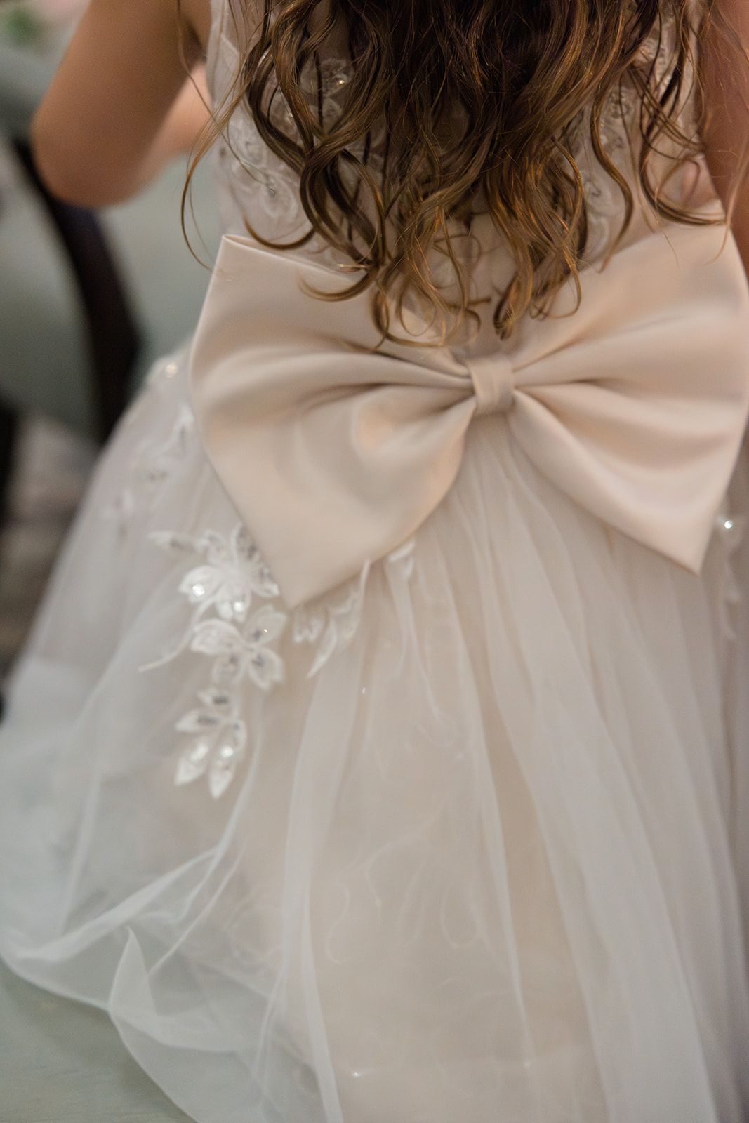 Close-up details of a delicate cream-colored satin bow adorning a wedding dress with tulle fabric.