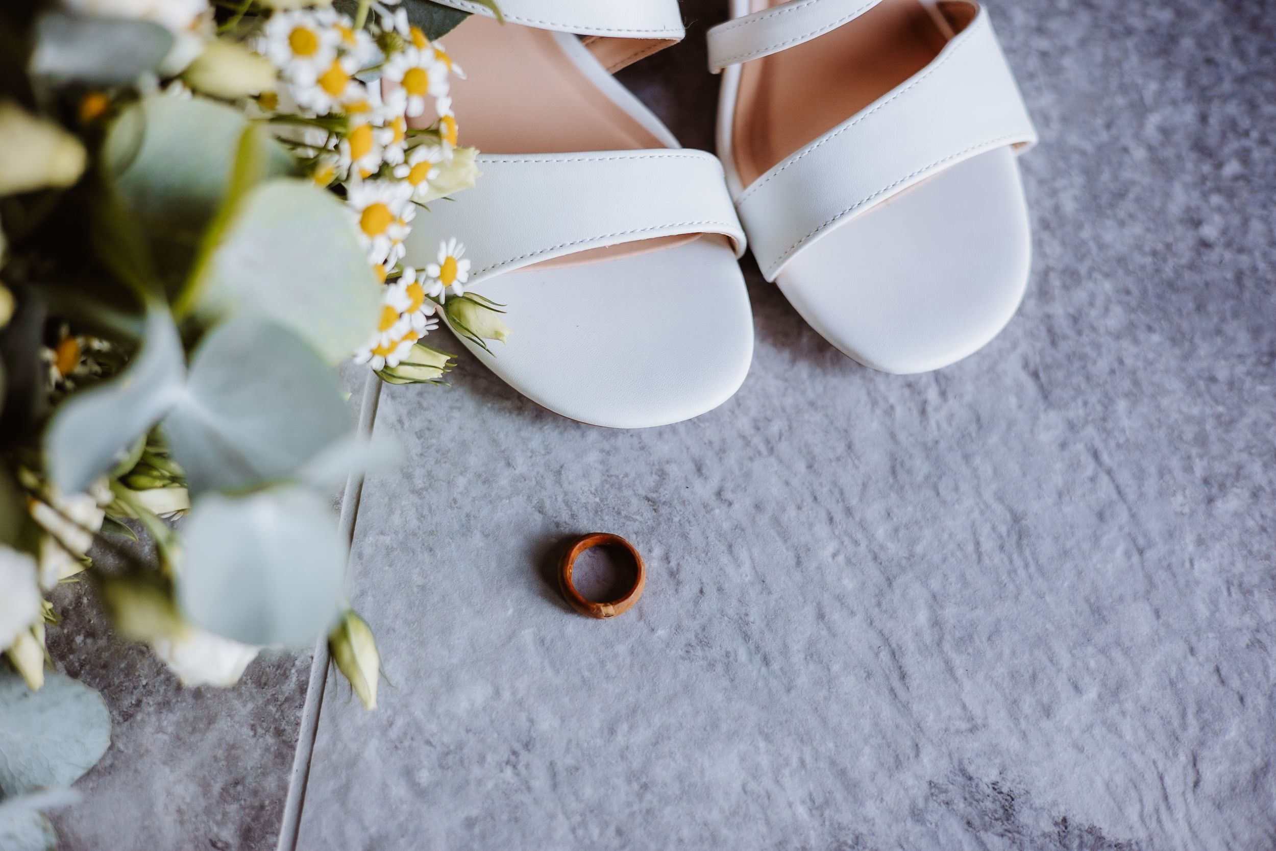 White ballet flats with delicate daisy flowers on a gray textured surface.