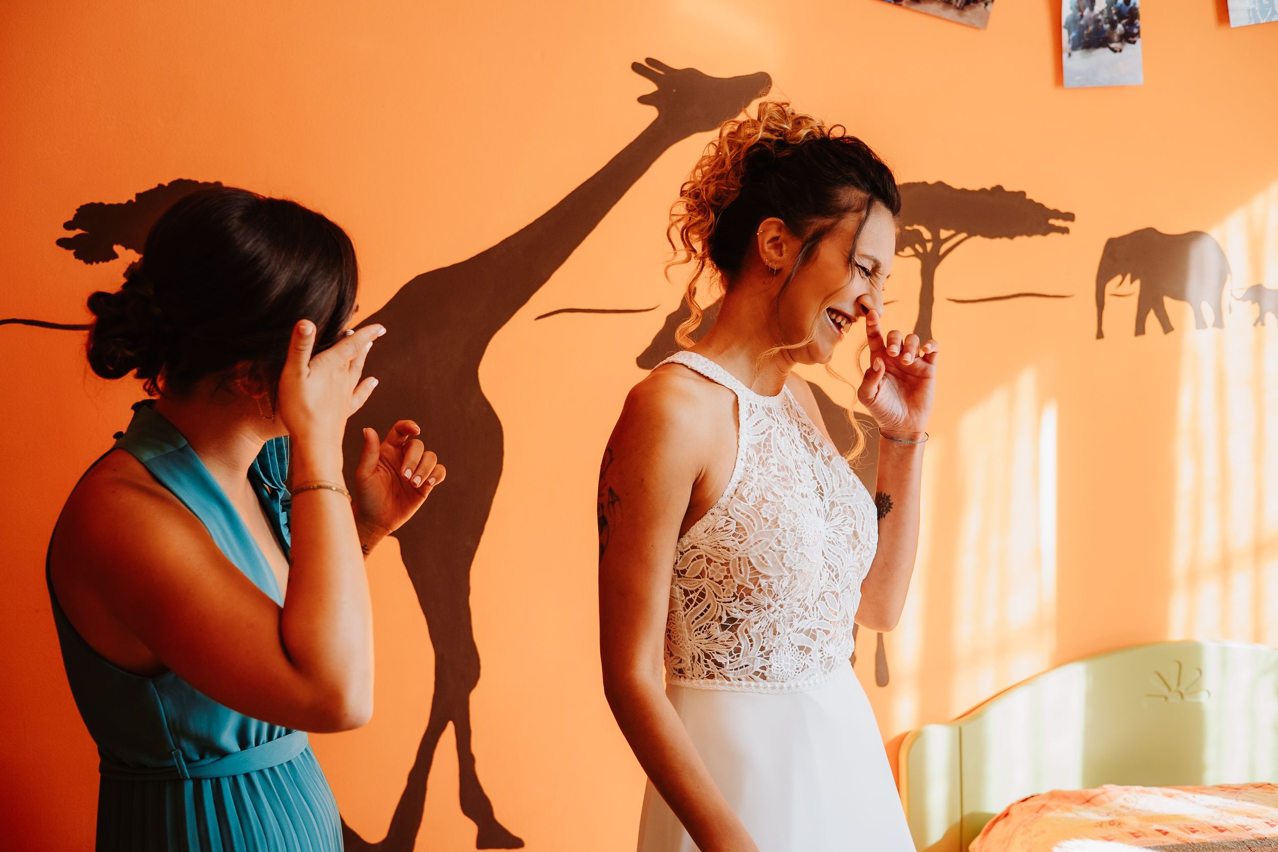 A row of bridesmaids in teal dresses stand with a bride in white during a wedding preparation moment.