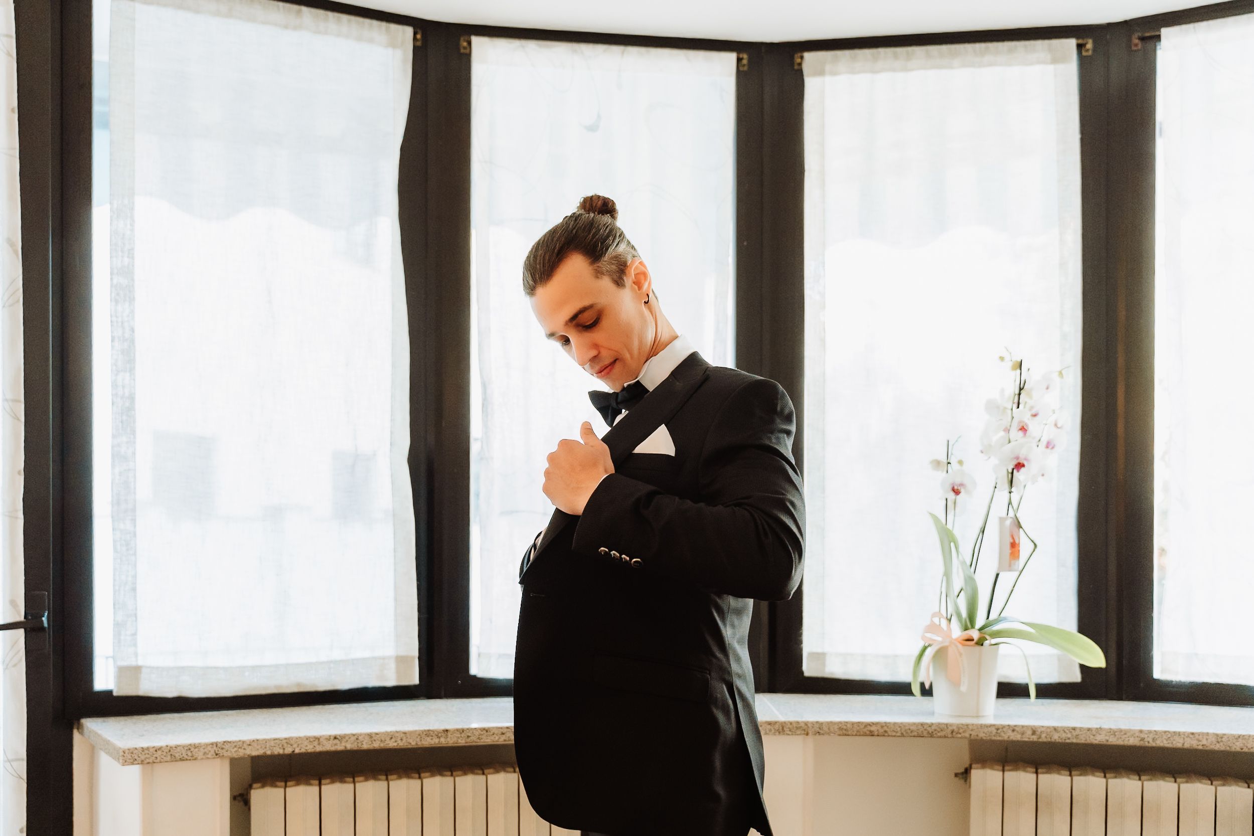 Professional waiter in black uniform pours wine into a glass at an elegant restaurant setting.