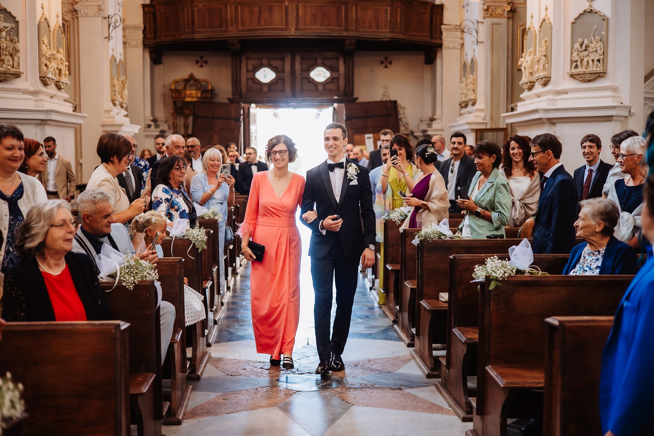 A church wedding ceremony with guests seated in wooden pews during an emotional moment at the altar.