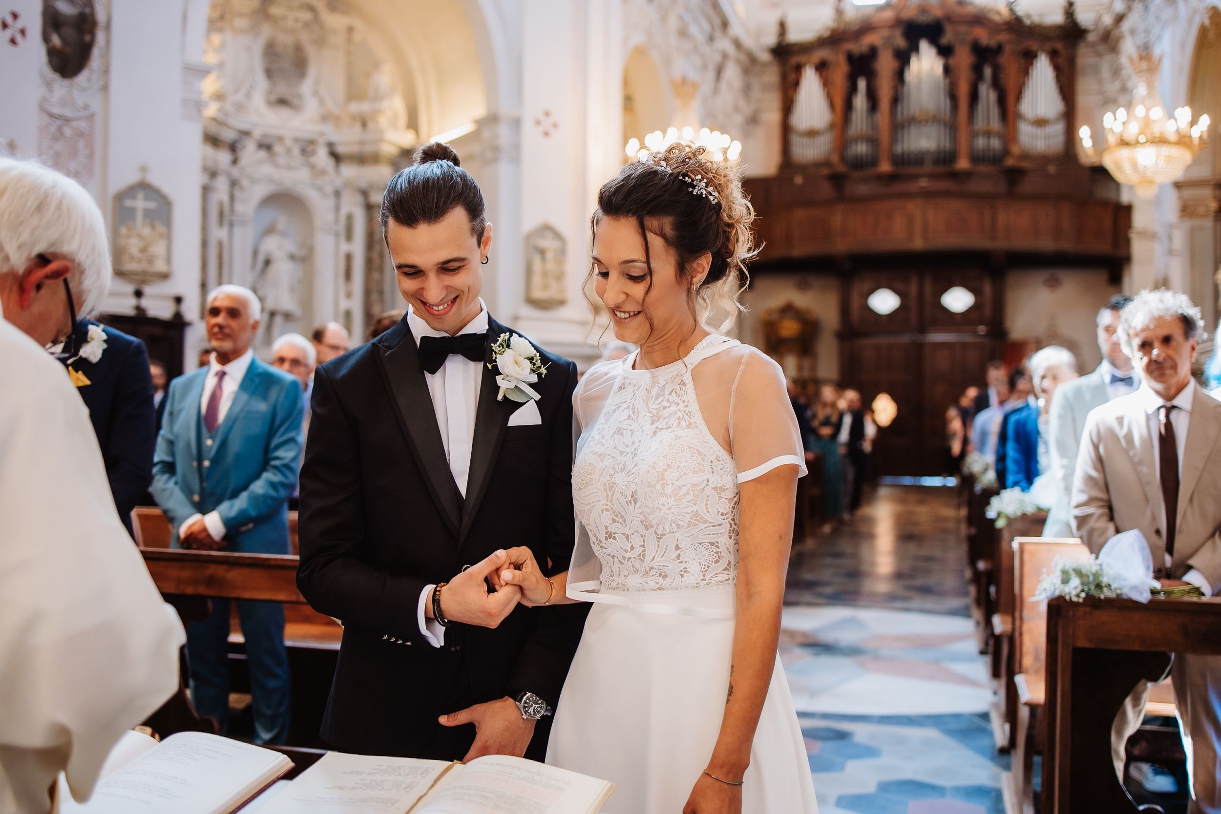 Elegant wedding ceremony in a grand cathedral with ornate architecture and glowing chandeliers.