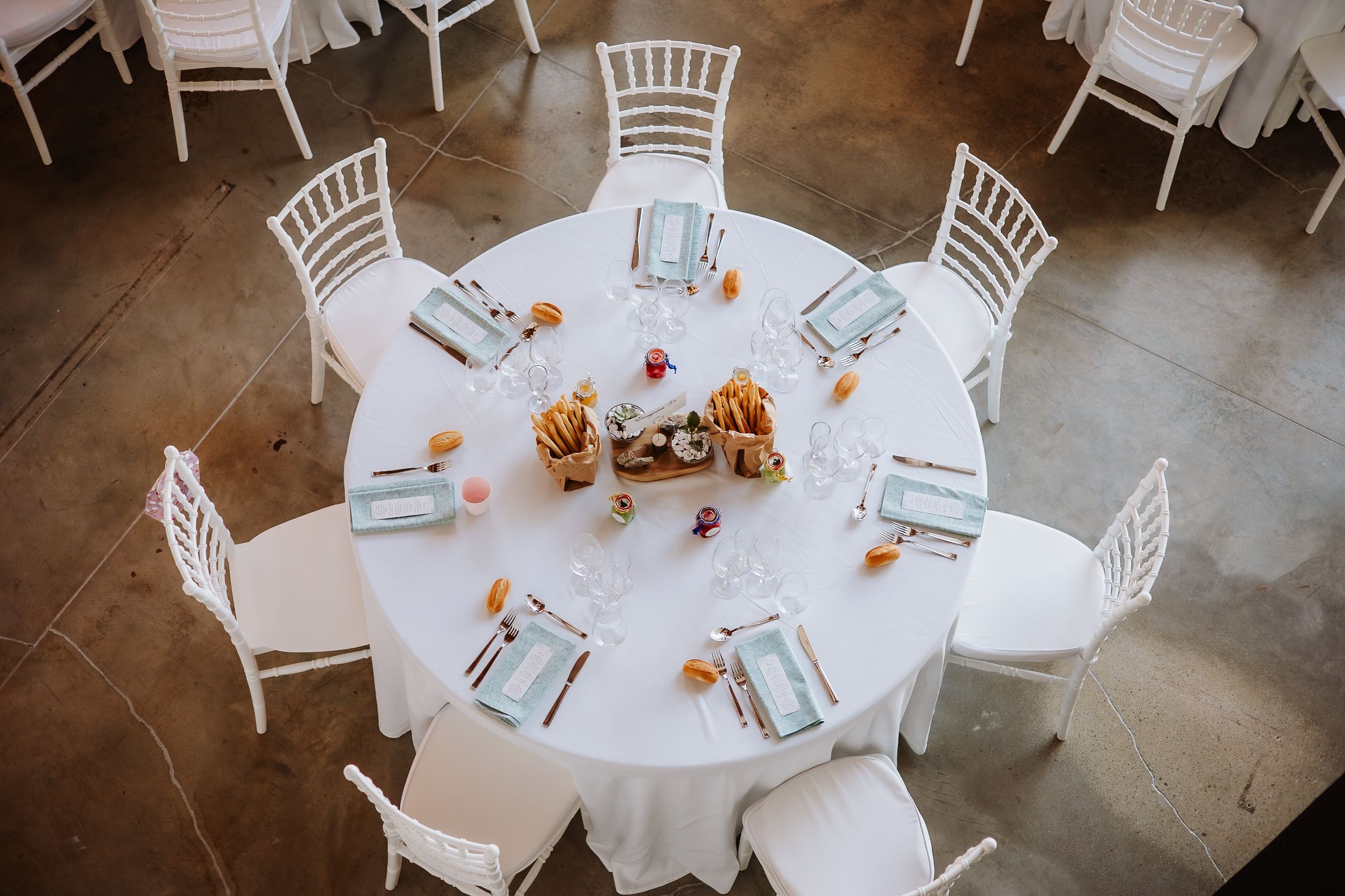 Overhead view of elegant white round dining tables with chiavari chairs set up for a formal event.