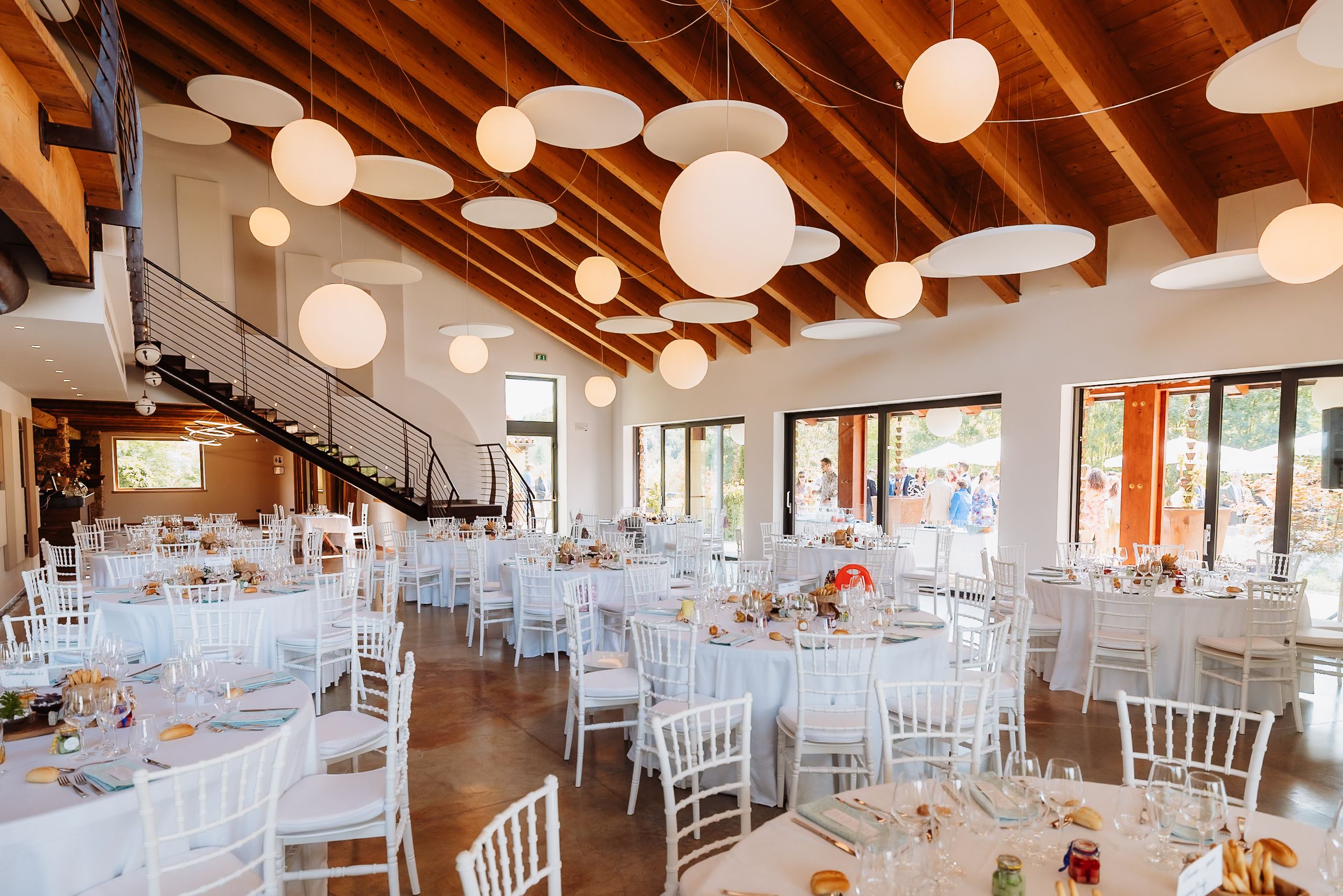 Elegant wedding reception venue with exposed wooden beams and white paper lanterns creating a warm, rustic atmosphere.