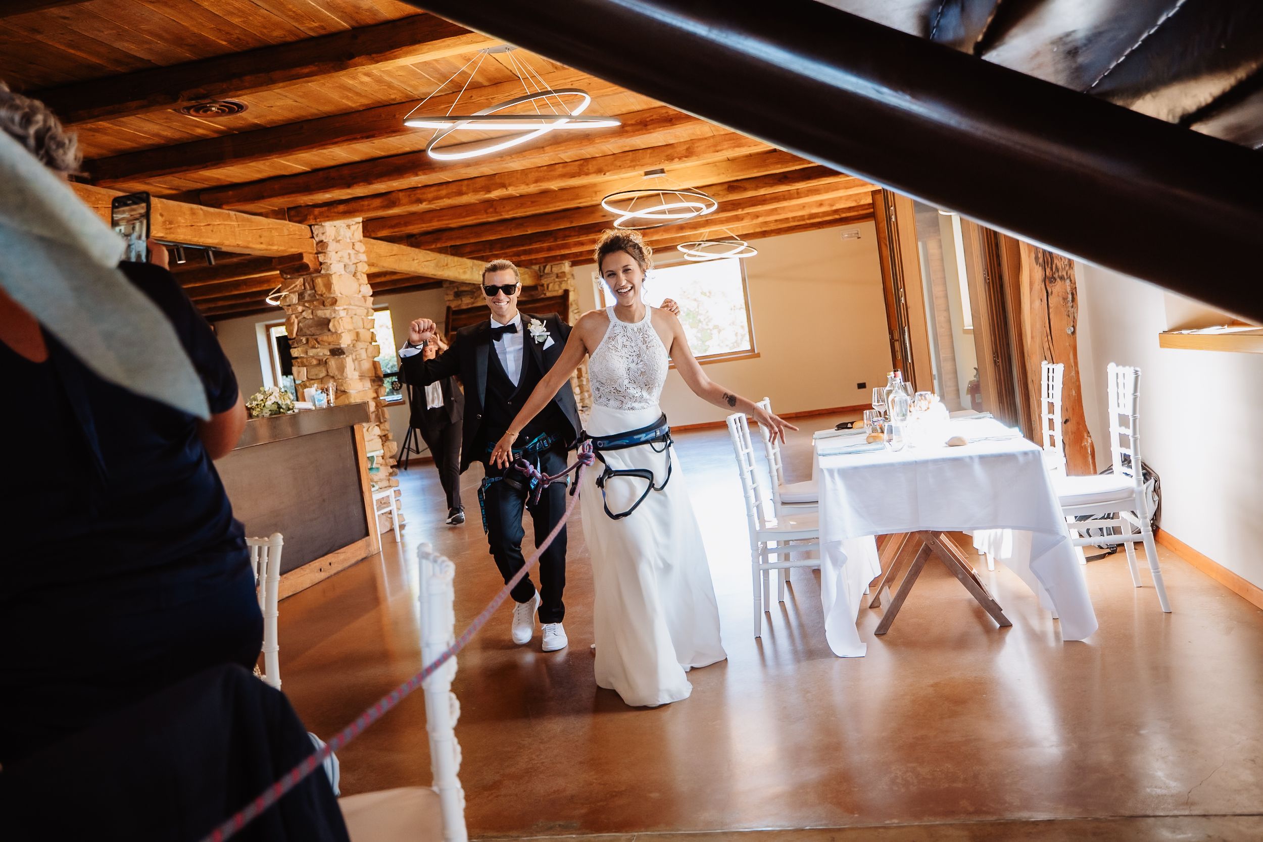 A panoramic sequence showing people dancing and moving across a bright wooden floor in an indoor venue.