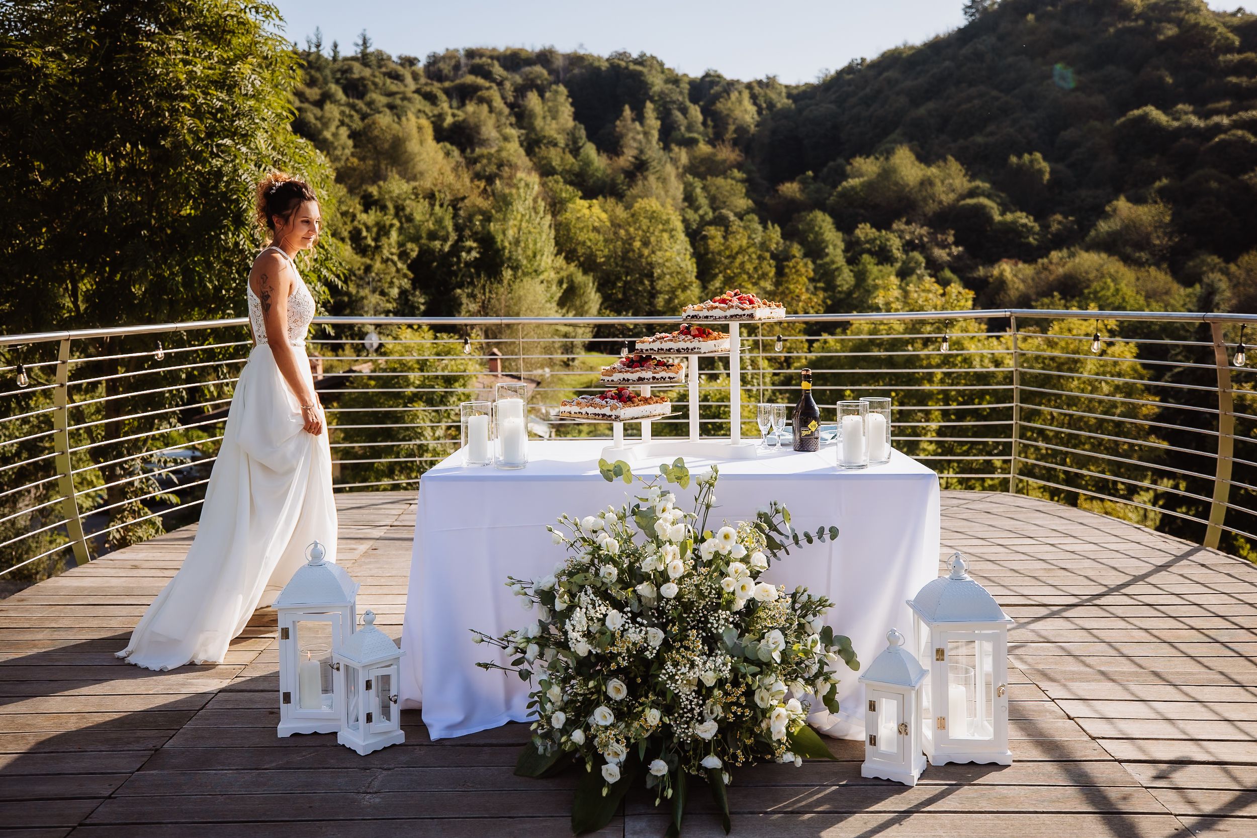 Elegant outdoor wedding ceremony setup with white chairs and floral arrangements on a scenic mountain deck.