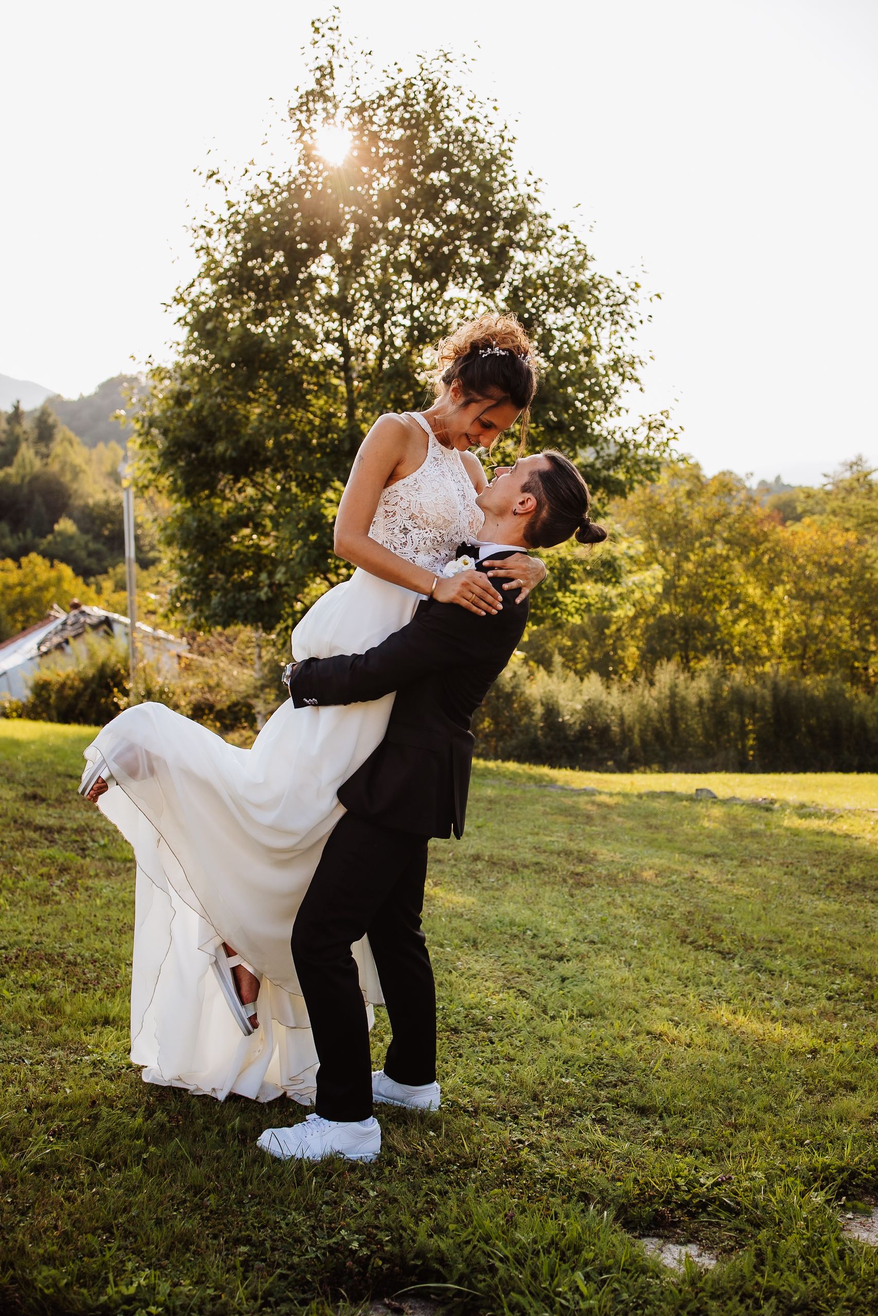 A romantic wedding couple shares intimate dance poses in a sunlit meadow at golden hour.