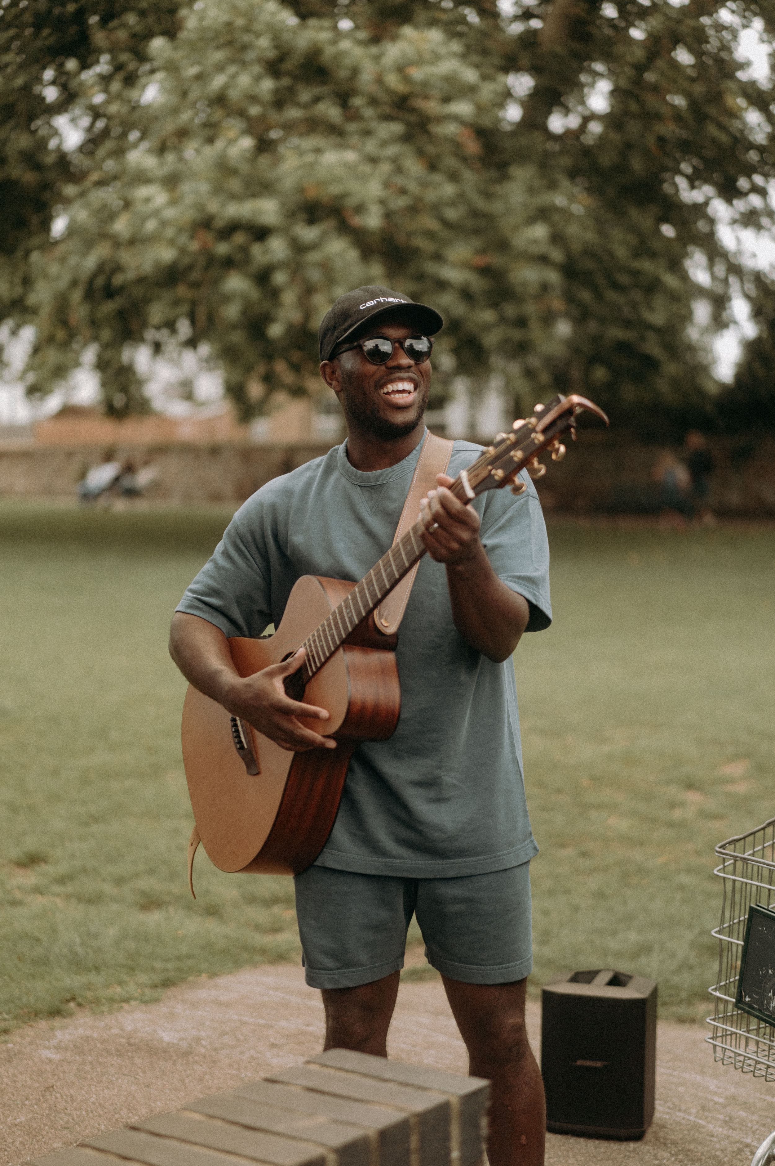 Man with a hat sunglasses, wearing a matching blue jersey & short playing a guitar
