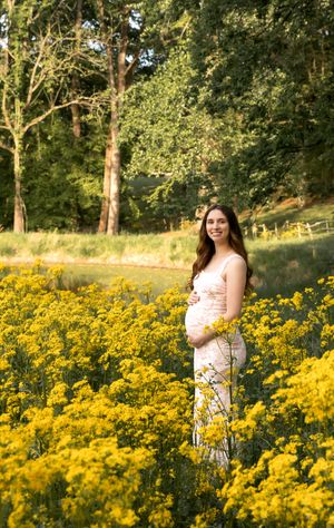 Maternity photo session in a field of vibrant yellow wildflowers during golden hour.