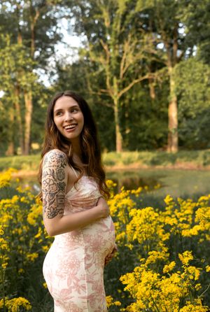 Joyful maternity photos captured in a meadow filled with blooming yellow flowers.