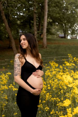 Artistic maternity photos showcasing tattoo details against backdrop of yellow flowers.