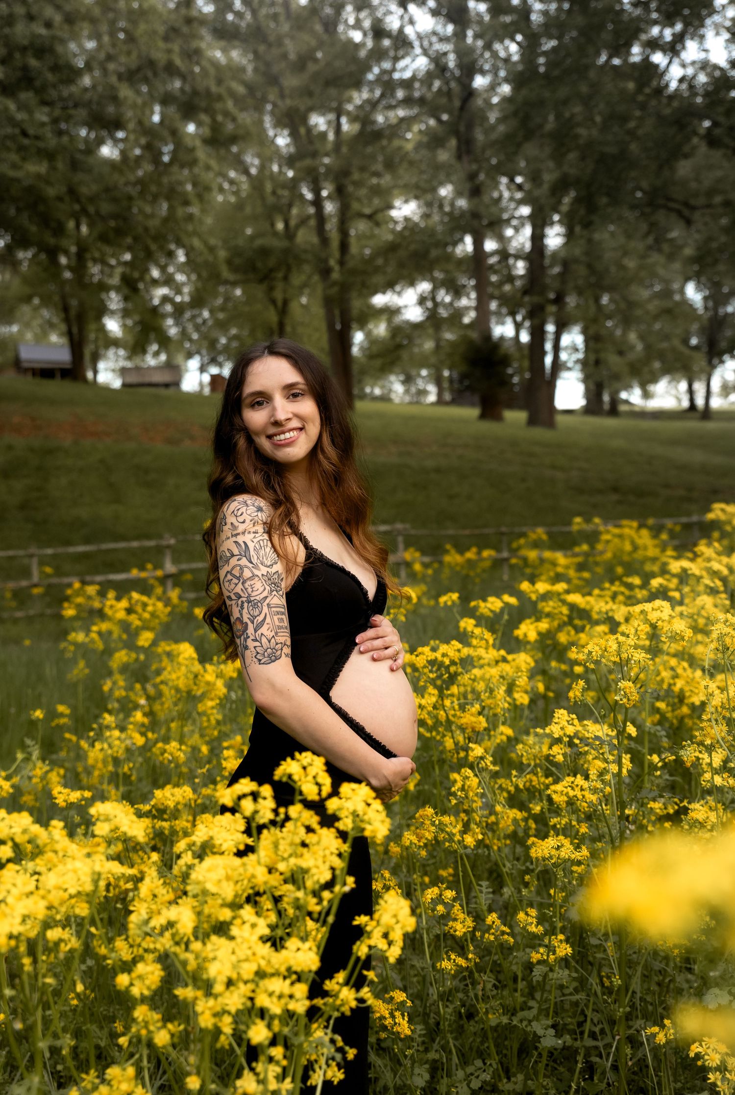 Natural maternity portraits taken in flowering meadow during sunset golden hour.