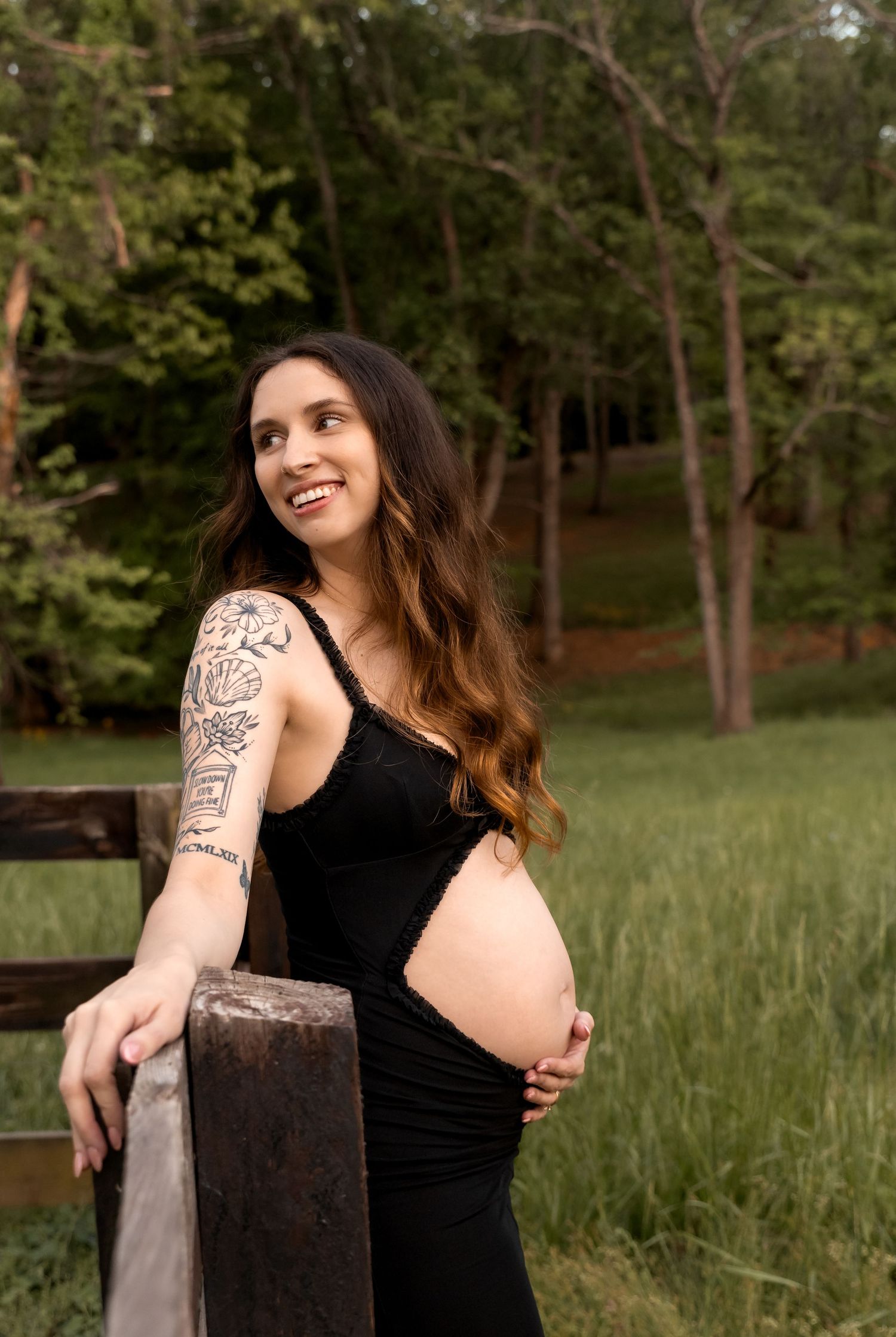 Rustic maternity photography with wooden fence and natural outdoor setting.