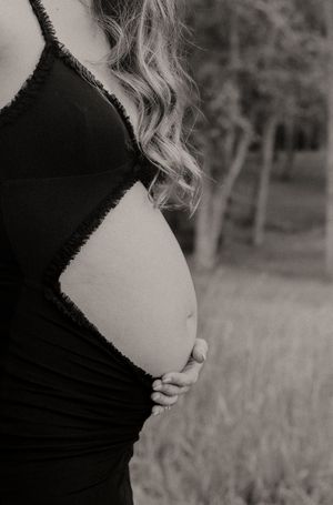 An artistic black and white side profile maternity photograph outdoors.