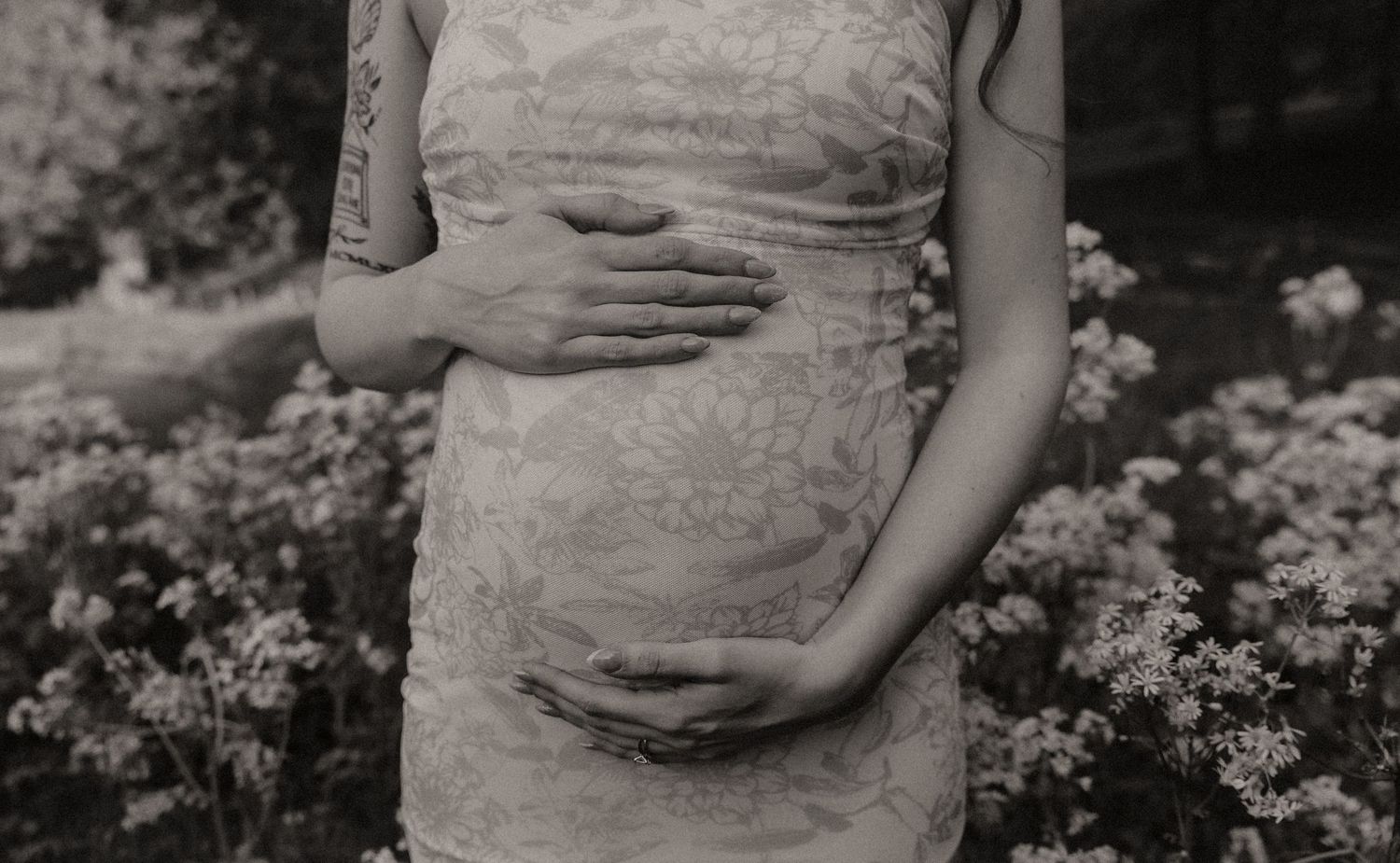 A vintage-style black and white photograph capturing a gentle moment during pregnancy.