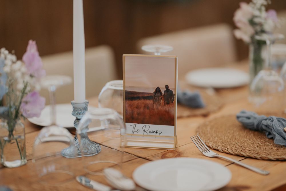 Wedding table centerpiece featuring a photo of the couple in a gold frame on a rustic wooden table.