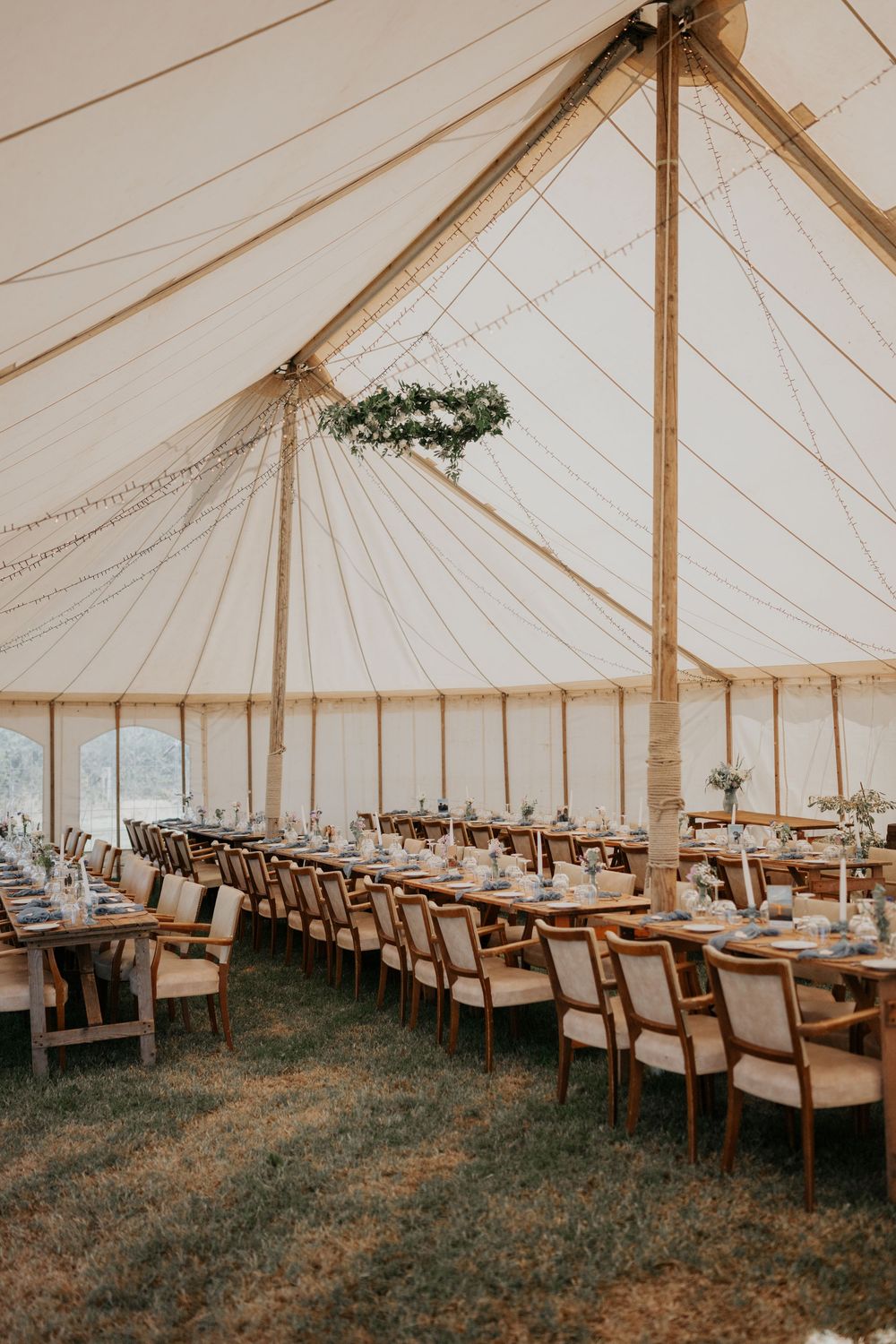 Stunning marquee wedding interior with soaring canvas ceiling, fairy lights, and a floral hoop chandelier.