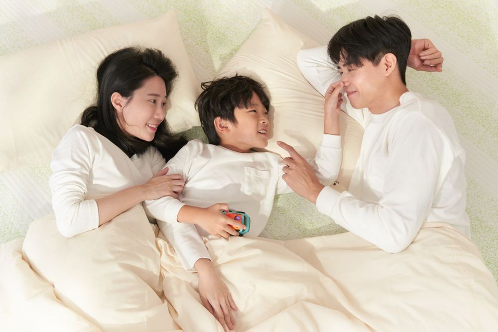 A series of intimate black and white photos showing a couple in white clothing lying together on a bed.